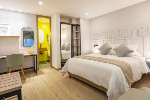 a bedroom with a bed and a desk and a mirror at Siete Balcones Hotel Coworking in Pasto