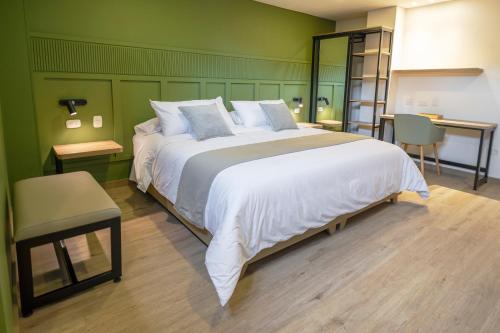 1 dormitorio con 1 cama blanca grande y paredes verdes en Siete Balcones Hotel y Coworking, en Pasto