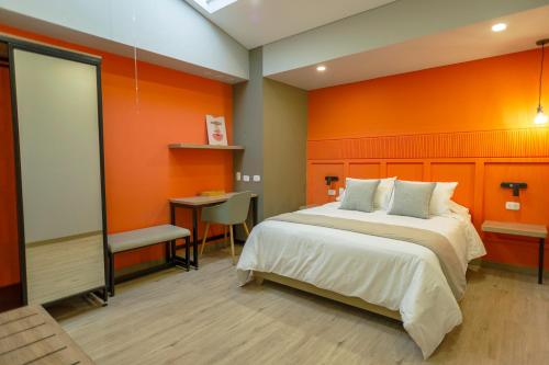 a bedroom with an orange wall and a bed at Siete Balcones Hotel Coworking in Pasto