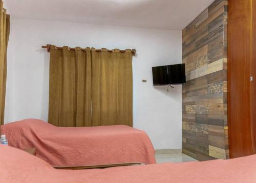 a bedroom with a bed and a flat screen tv at Departamento 3. Túumben Ché in Valladolid