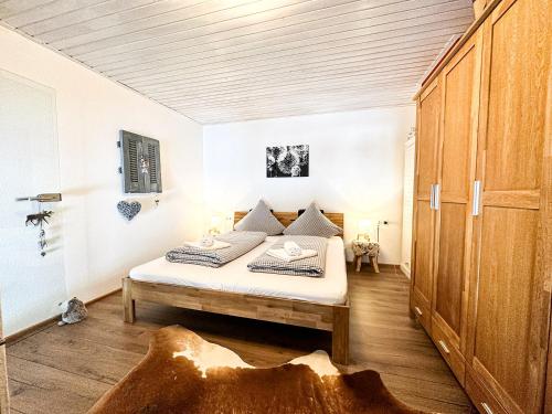 Schlafzimmer mit einem Bett und einem Holzschrank in der Unterkunft FEWO Yeti in Oberstaufen
