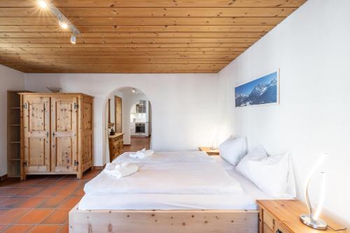 sypialnia z łóżkiem i drewnianym sufitem w obiekcie Chasina Bagnera w mieście Scuol