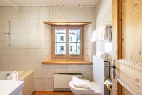 łazienka z toaletą i oknem w obiekcie Chasina Bagnera w mieście Scuol