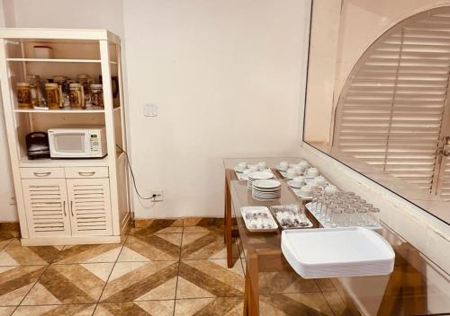 a kitchen with a table with cups and a microwave at Hotel Prudente RP in Ribeirão Preto