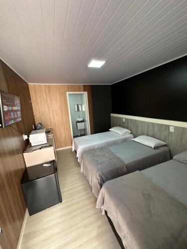 a hotel room with three beds and a telephone at Loft Lux 5 in Chapecó