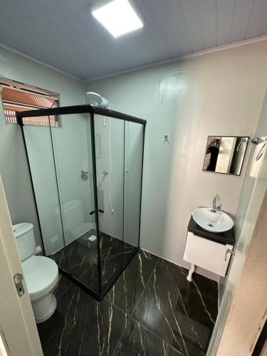 a bathroom with a shower and a toilet and a sink at Loft Lux 5 in Chapecó