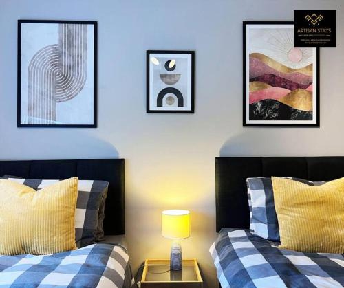 two beds in a room with pictures on the wall at The Rose Garden of Basildon in the Heart of Basildon by Artisan Stays I Weekly or Monthly Stay Offer I Pvt Parking I Sleeps 6 in Basildon