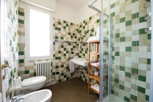 La salle de bains est pourvue de murs carrelés verts et blancs. dans l'établissement Luisella Apartments, à Albenga