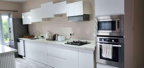 a white kitchen with a stove and a microwave at TIE-2 bedroom luxury home in La Fargue