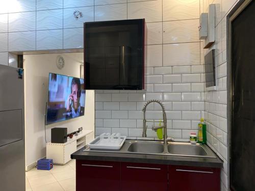 a kitchen with a sink and a tv on the wall at Villa Palmeraie in Brazzaville