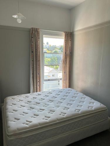 uma cama branca num quarto com uma janela em Ballymena House em Dunedin