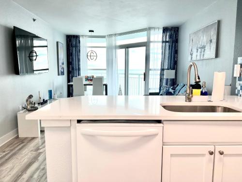 a white kitchen with a sink and a large window at Stylish Oceanview Getaway Modern 1BR at Carolinian Resort" in Myrtle Beach
