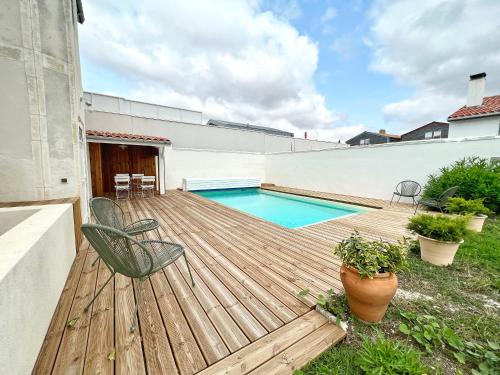 une terrasse en bois avec une piscine dans une arrière-cour dans l'établissement La Sauvagère - Piscine, à La Rochelle
