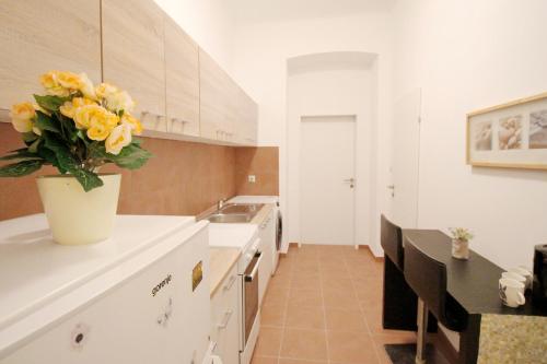 a kitchen with a vase of yellow roses on the counter at Family apartment in Brigittenau in Vienna