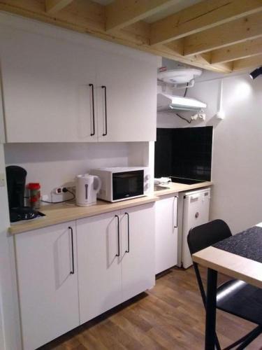 una pequeña cocina con armarios blancos y microondas en Studio à la plage, en Donville-les-Bains