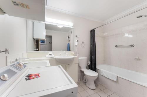 a white bathroom with a sink and a toilet and a tub at Horizons 216 - Deluxe Lake Front Studio l Pool l Tennis l Air-Con in Jindabyne
