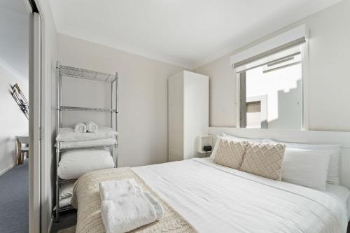 a white bedroom with a large bed and a mirror at Horizons 216 - Deluxe Lake Front Studio l Pool l Tennis l Air-Con in Jindabyne