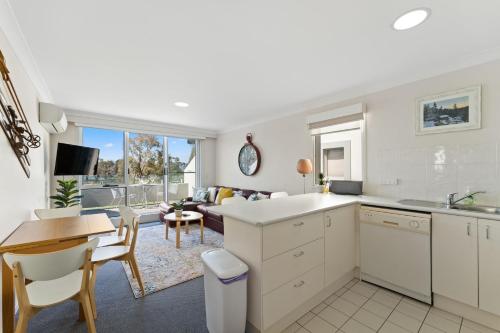 a kitchen and living room with a table and chairs at Horizons 216 - Deluxe Lake Front Studio l Pool l Tennis l Air-Con in Jindabyne