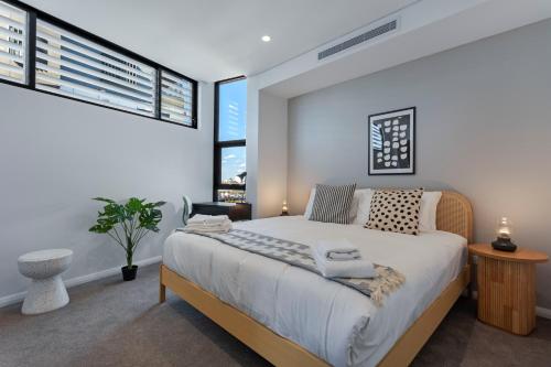 ein Schlafzimmer mit einem großen Bett und zwei Fenstern in der Unterkunft KULA Wollongong in Wollongong