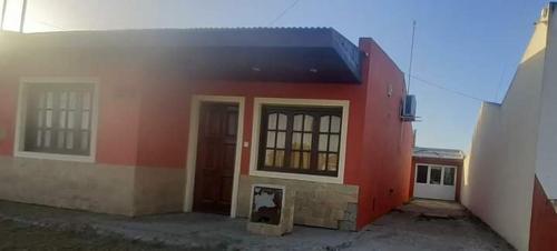 a red building with a dog sitting outside of it at Mis Vacaciones in Necochea
