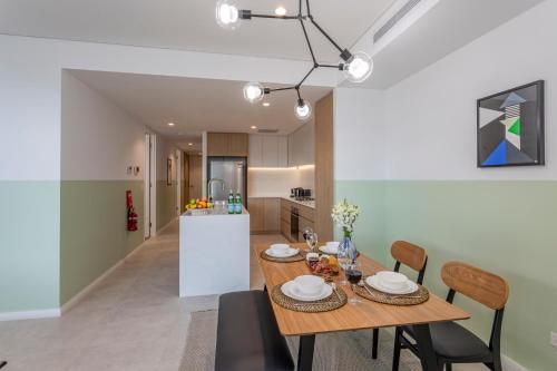 cocina y comedor con mesa de madera y sillas en KULA Wollongong en Wollongong