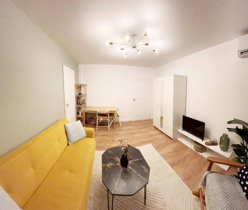 uma sala de estar com um sofá amarelo e uma mesa em Lola’s apartament close to city center em Bucareste