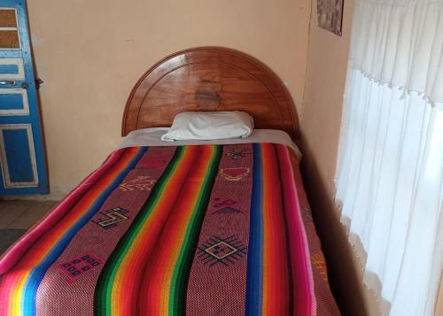 a bed with a colorful blanket on top of it at BLUE SKY Amantani Lodge in Ocosuyo