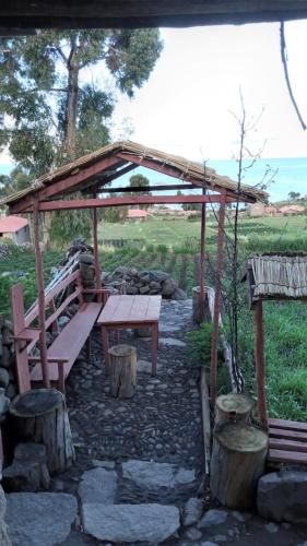 BLUE SKY Amantani Lodge في Ocosuyo: طاولة نزهة ومقعد تحت جناح خشبي