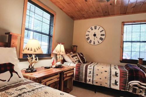 a bedroom with two beds and a clock on the wall at Woods Upon a Time Remodeled Cabin with Fireplace, Pond View & Firepit - Your Getaway Story Awaits! in Murphy