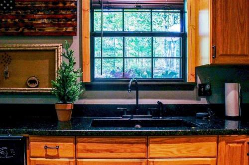 a kitchen with a sink and a window at Woods Upon a Time Remodeled Cabin with Fireplace, Pond View & Firepit - Your Getaway Story Awaits! in Murphy