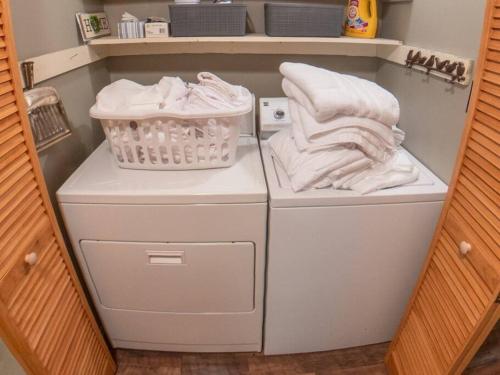 a laundry room with white clothes and a basket at Woods Upon a Time Remodeled Cabin with Fireplace, Pond View & Firepit - Your Getaway Story Awaits! in Murphy