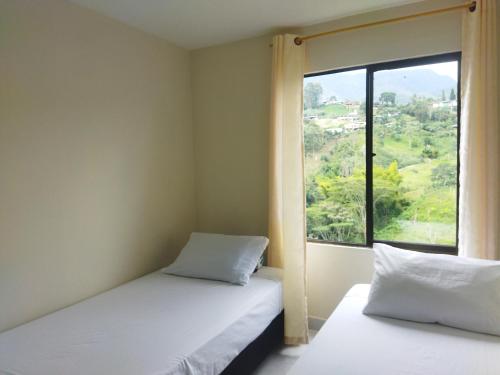 two beds in a room with a large window at Canto del rio in Jardin