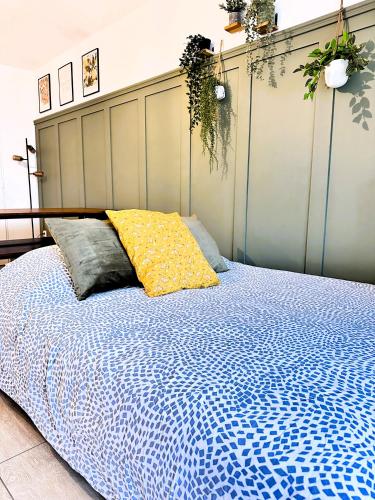 a bed with a blue comforter and a yellow pillow at *New* Livy 6 pax Appart Disney in Serris