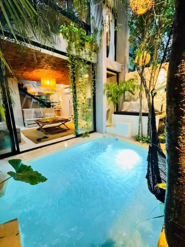 an indoor pool with a hammock in a house at Luz de Luna Tulum Villa in Tulum