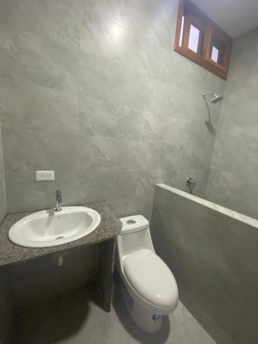 uma casa de banho com um WC branco e um lavatório. em Penguin House em Puerto Villamil