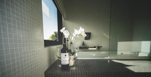 a bottle of wine and flowers on a counter in a bathroom at The Roozen Residence in Prevelly