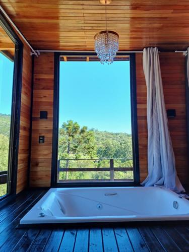 a tub in a room with a large window at Recanto do Ipê (cabana 02) in Urubici