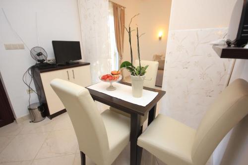 einen kleinen Esstisch mit weißen Stühlen und einem TV in der Unterkunft Apartments by the sea Kolocep, Elafiti - 2182 in Koločep