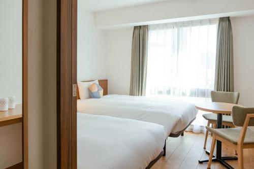 Habitación de hotel con 2 camas y mesa en OMO5 Kyoto Sanjo by Hoshino Resorts en Kioto