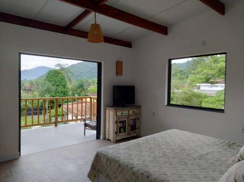 um quarto com uma cama e vista para uma varanda em Casa 3 suítes vista natureza em Ubatuba