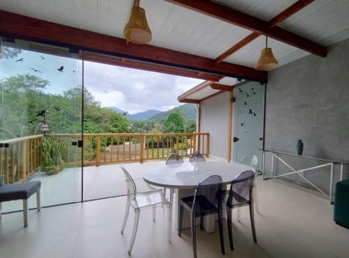a dining room with a table and chairs on a balcony at Casa 3 suítes vista natureza in Ubatuba