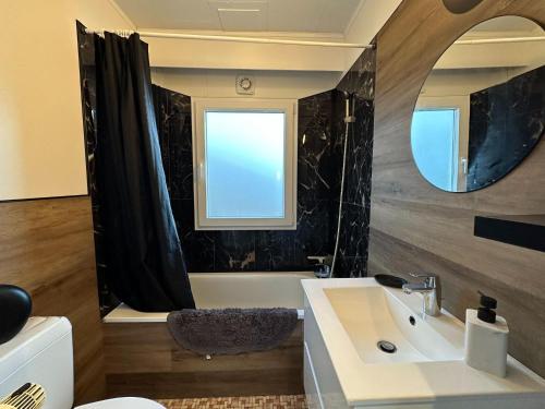 La salle de bains est pourvue d'un lavabo, d'une baignoire et d'un miroir. dans l'établissement Cosy holiday home in Andenne with terrace, à Andenne