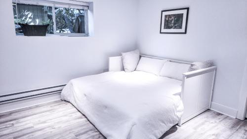Un dormitorio blanco con una cama y una ventana. en Small Private Studio at Kitsilano Beach, en Vancouver