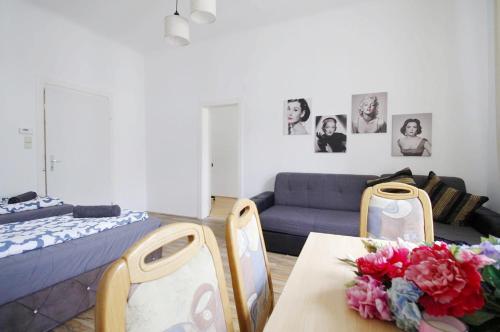 ein Wohnzimmer mit einem Sofa und einem Tisch mit Blumen darauf in der Unterkunft Comfortable rooms near Schönbrunn Palace in Wien