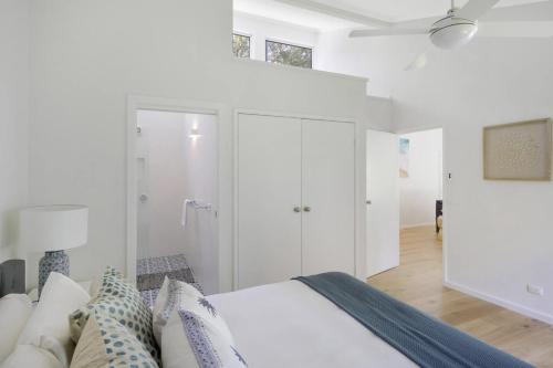 Macmasters BeachにあるFamily Friendly Beach House - 5mins walk to the beachの白いベッドルーム(ベッド1台、天井ファン付)