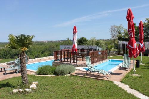 een zwembad met 2 stoelen en parasols naast bij Apartments and rooms with a swimming pool Bacva, Central Istria - Sredisnja Istra - 7638 in Višnjan