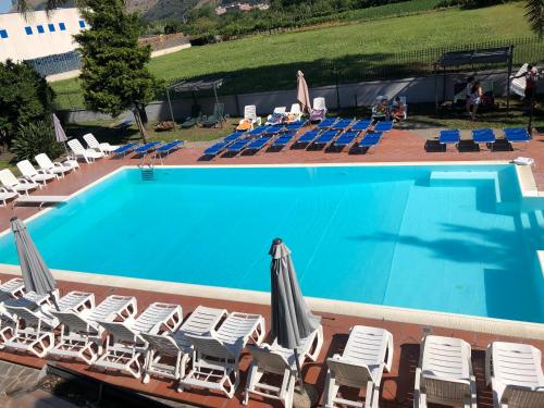 a swimming pool with chairs and an umbrella at IN BLOOM ROOM b&b in Castel San Giorgio