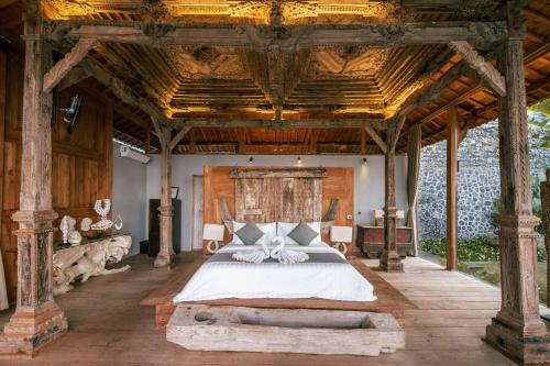 a bedroom with a large bed with a wooden ceiling at Villa Joglovina Lovina in Lovina