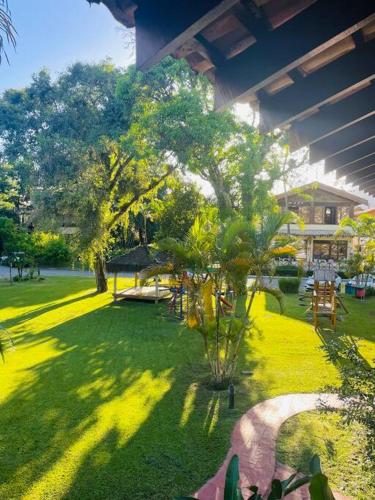 a green yard with a tree and a building at B12 Casa em Maresias condomínio a 50 metros da praia in Maresias