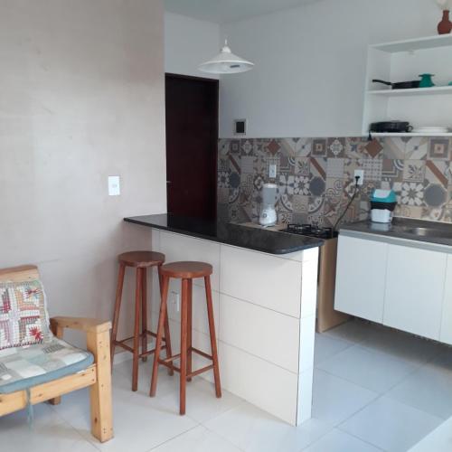 uma cozinha com um balcão e bancos num quarto em Pousada Caribe Milagrense em São Miguel dos Milagres